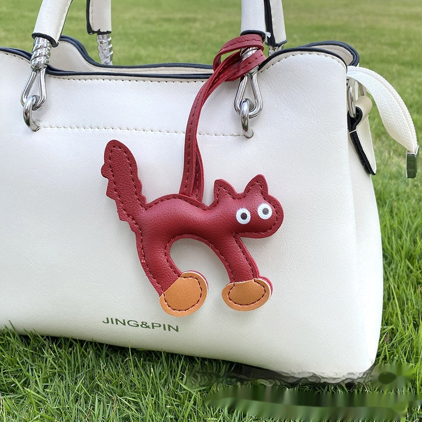 Mini cat pendant clipped onto bag strap